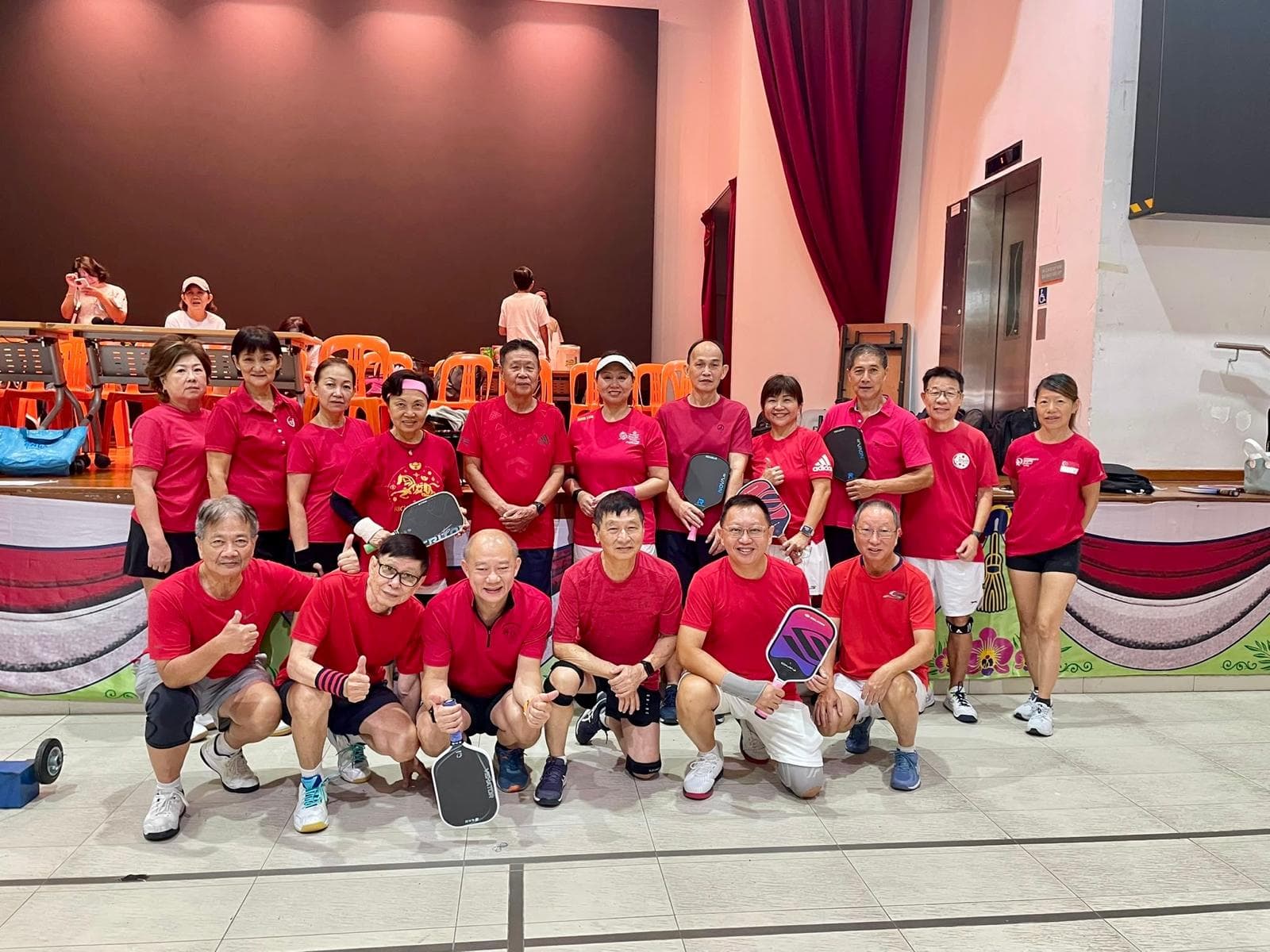 A group of players in red team shirts pose together courtside.